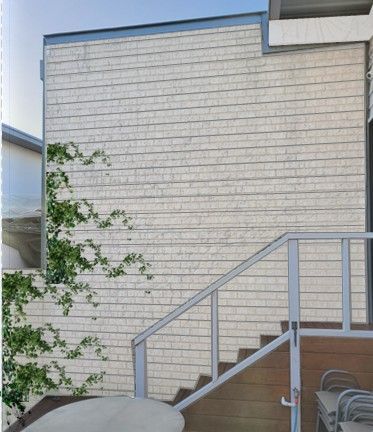Exterior of a building with light-colored, horizontal siding, a staircase, and a deck.