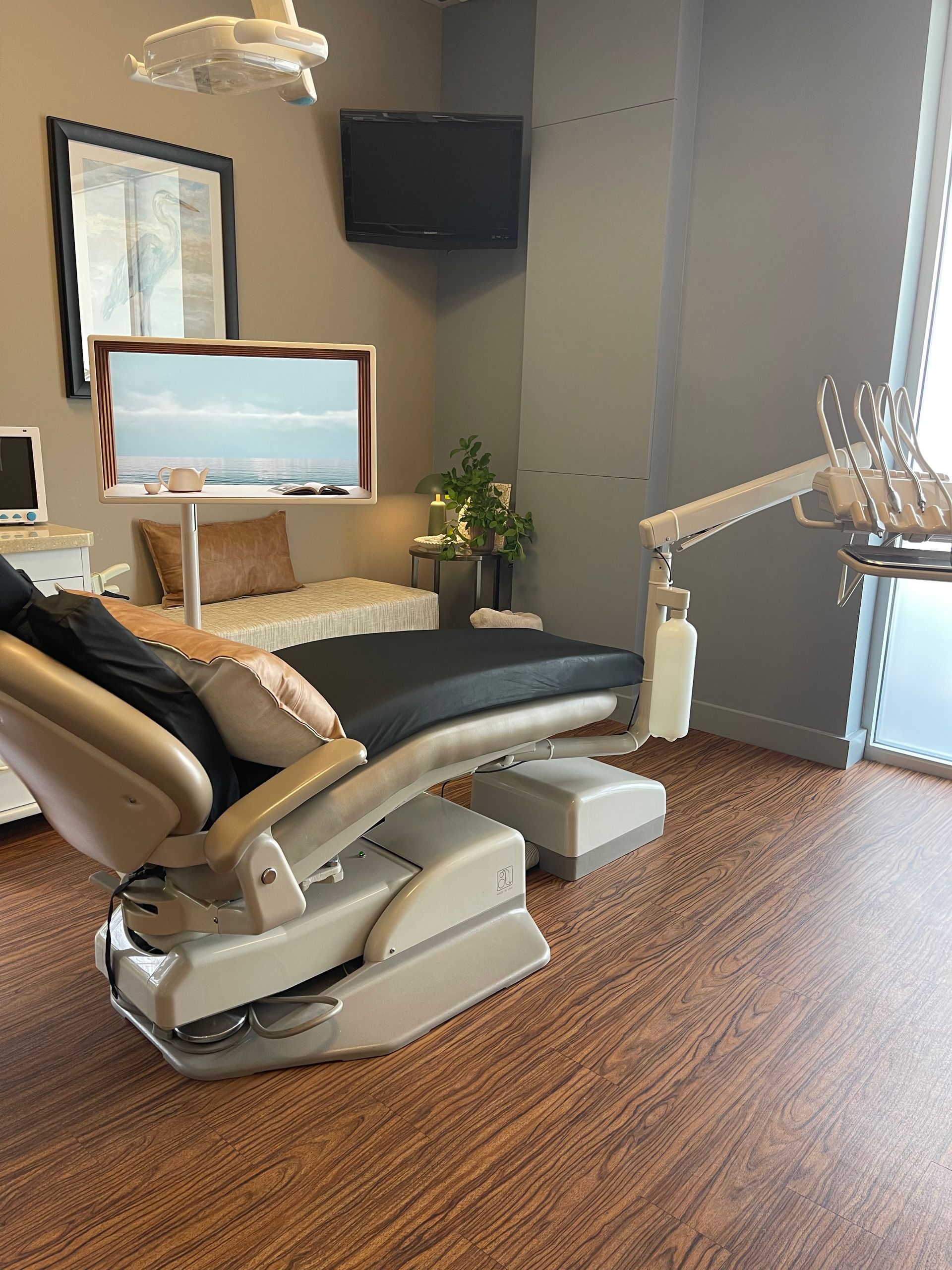 Dentist using a drill on a patient's open mouth; dental tools, gloved hands, bright lights.