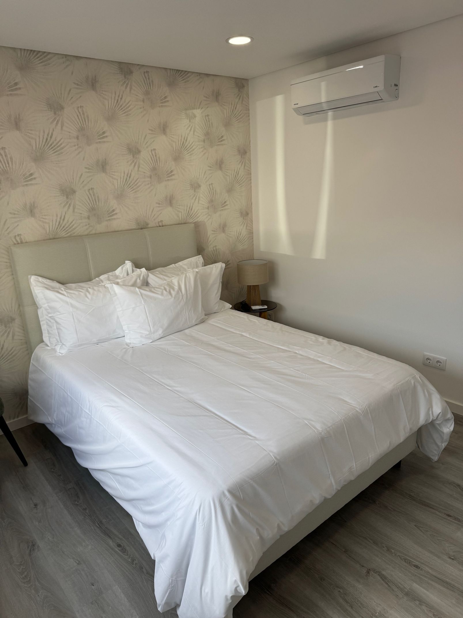 A bedroom with a king size bed and white sheets.