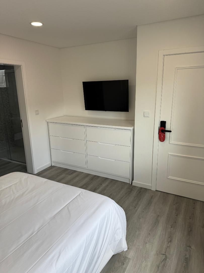A bedroom with a bed and a television on the wall