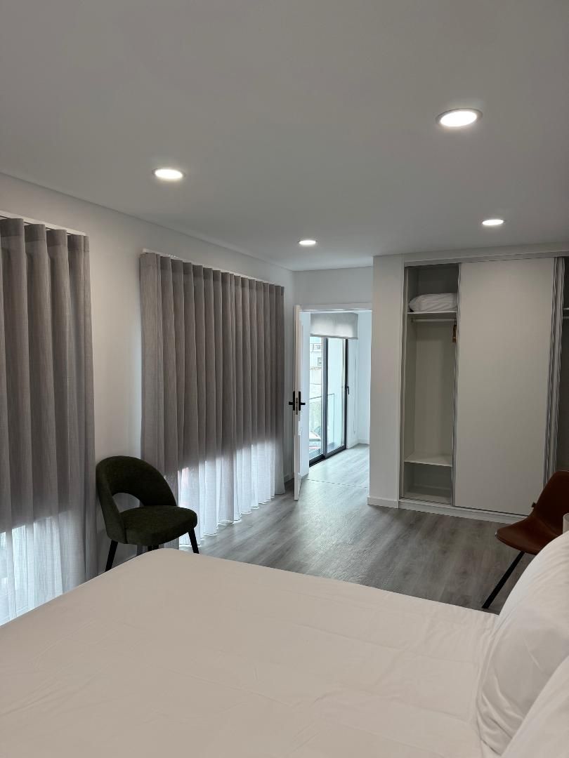 A hotel room with a bed , chair , and closet.