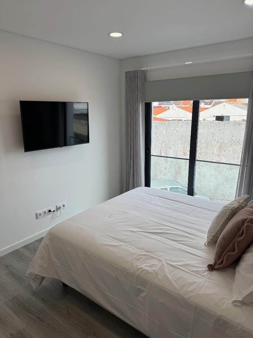 A bedroom with a large bed and a flat screen tv on the wall.