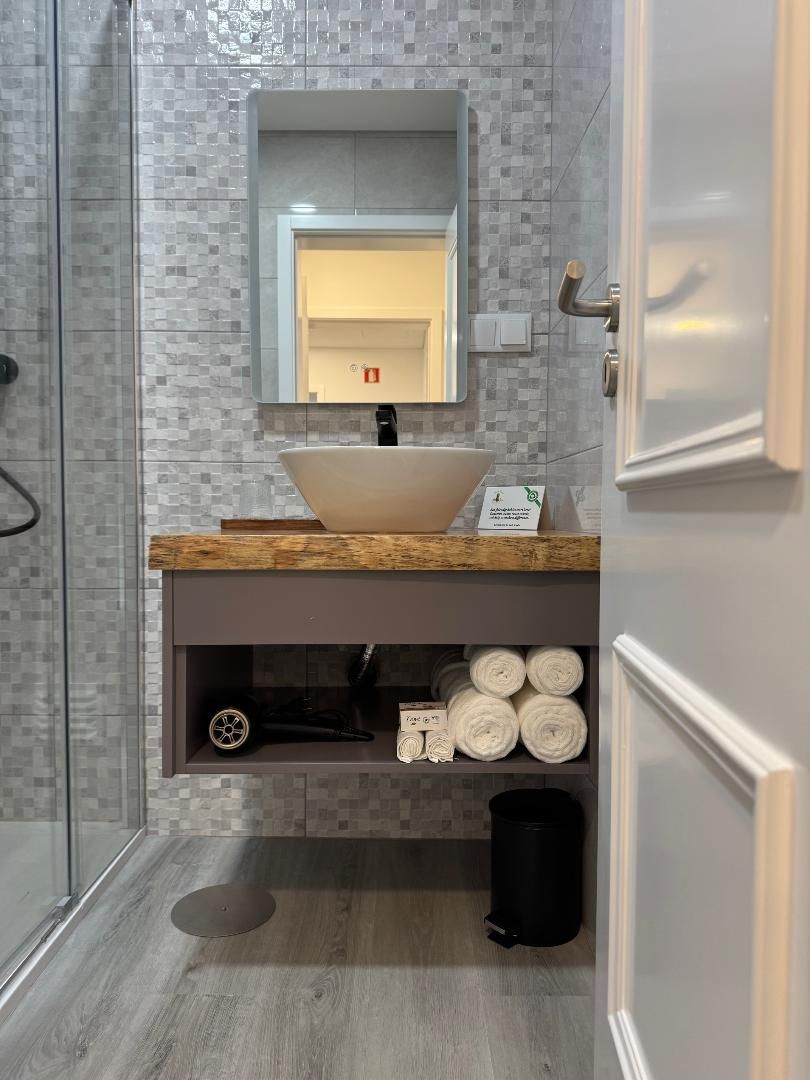 A bathroom with a sink , mirror and towels on the shelf.
