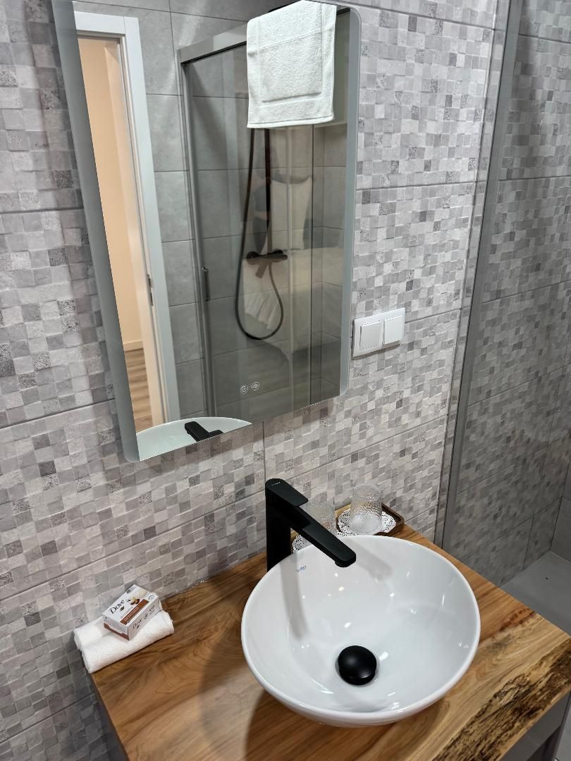 A bathroom with a sink , mirror and shower.