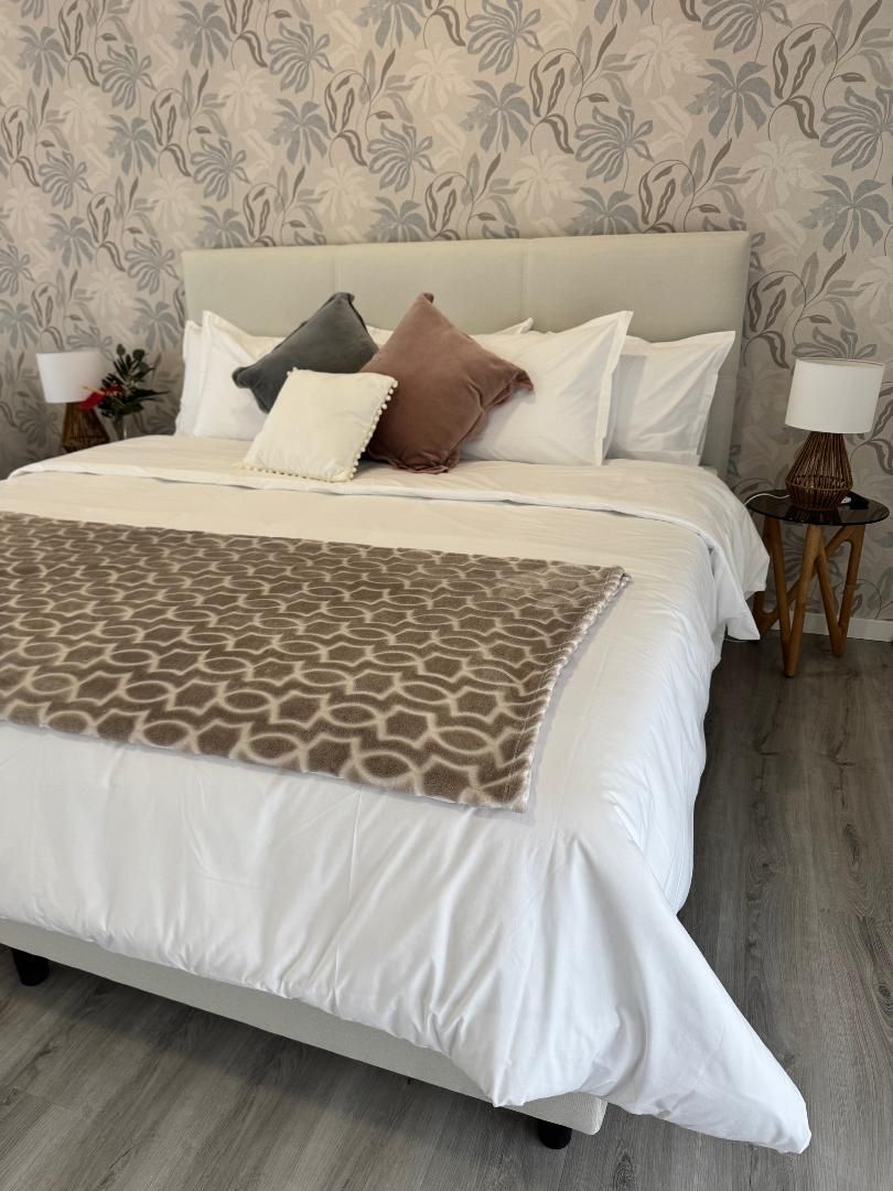A bed with white sheets and pillows in a bedroom.
