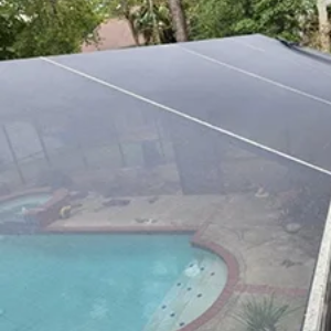 A group of professionals in a brick-walled office meeting around a table, listening as a person presents on a laptop.