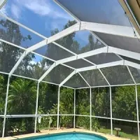 A group of professionals in a brick-walled office meeting around a table, listening as a person presents on a laptop.