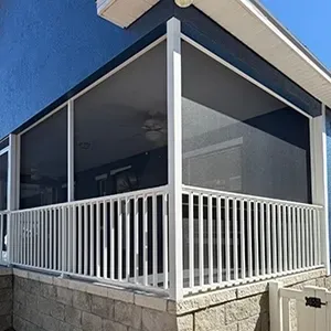 A group of professionals in a brick-walled office meeting around a table, listening as a person presents on a laptop.