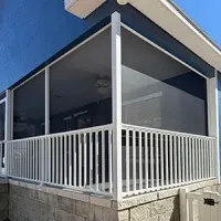 A group of professionals in a brick-walled office meeting around a table, listening as a person presents on a laptop.