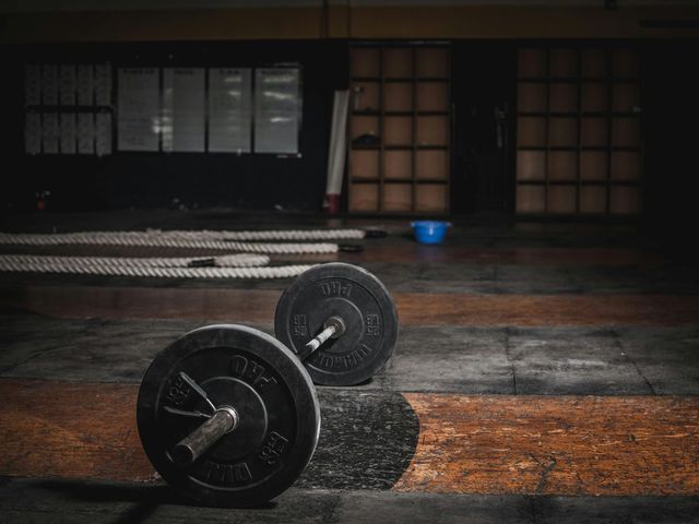 A pair of barbells sitting on top of a wooden floor in a gym.