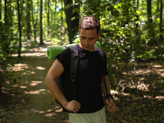 A man with a backpack is walking through the woods.