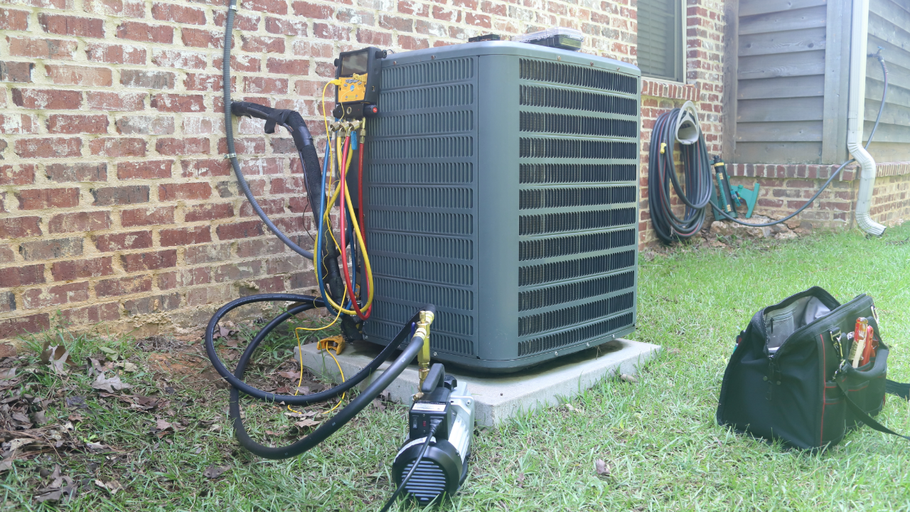 An air conditioner is being installed on the side of a brick building.