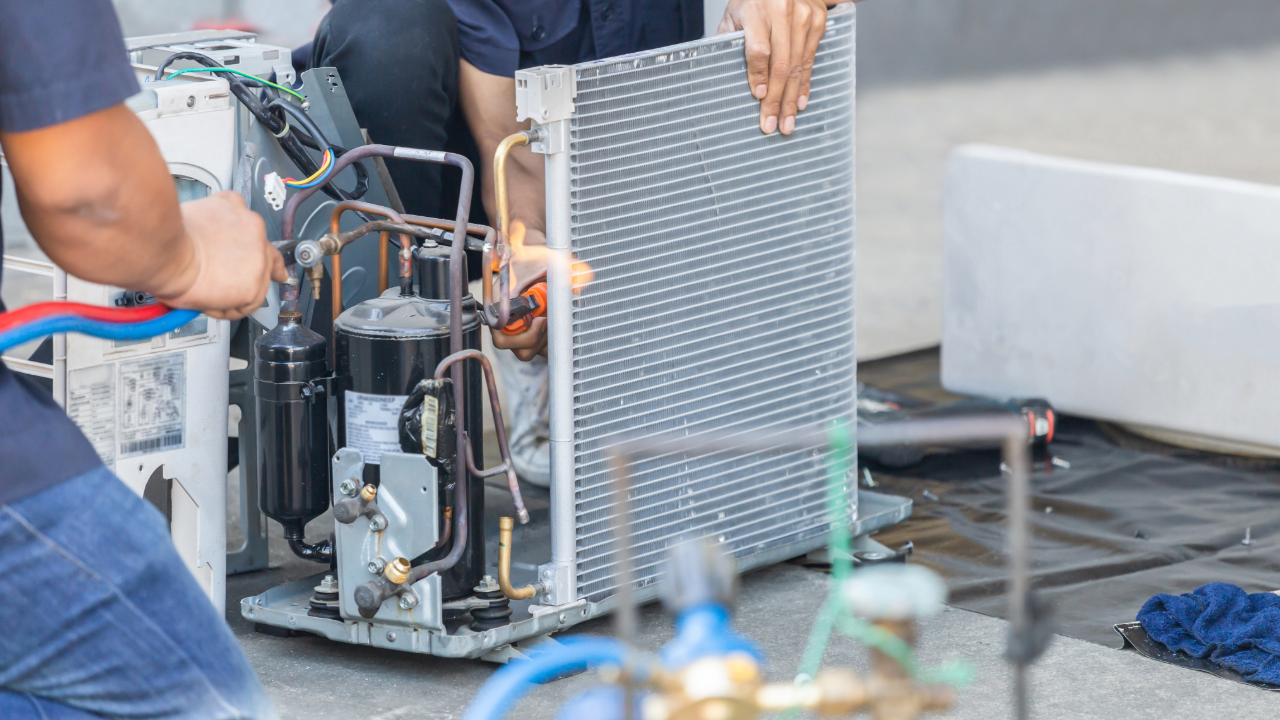 A man is working on an air conditioner on the ground.