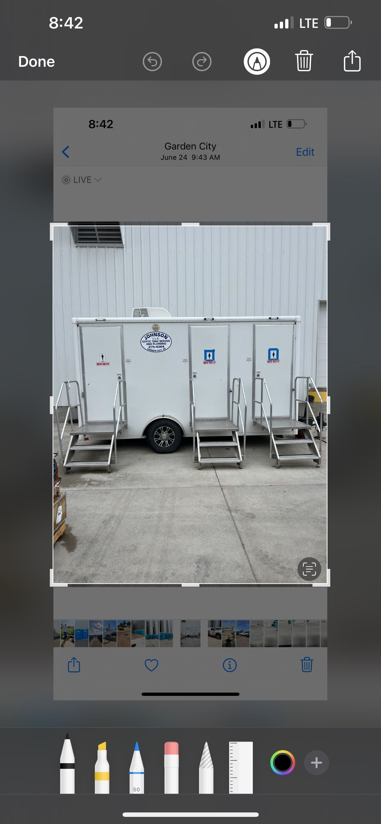 A white trailer with three portable restrooms, with metal steps in front. Gray concrete ground.