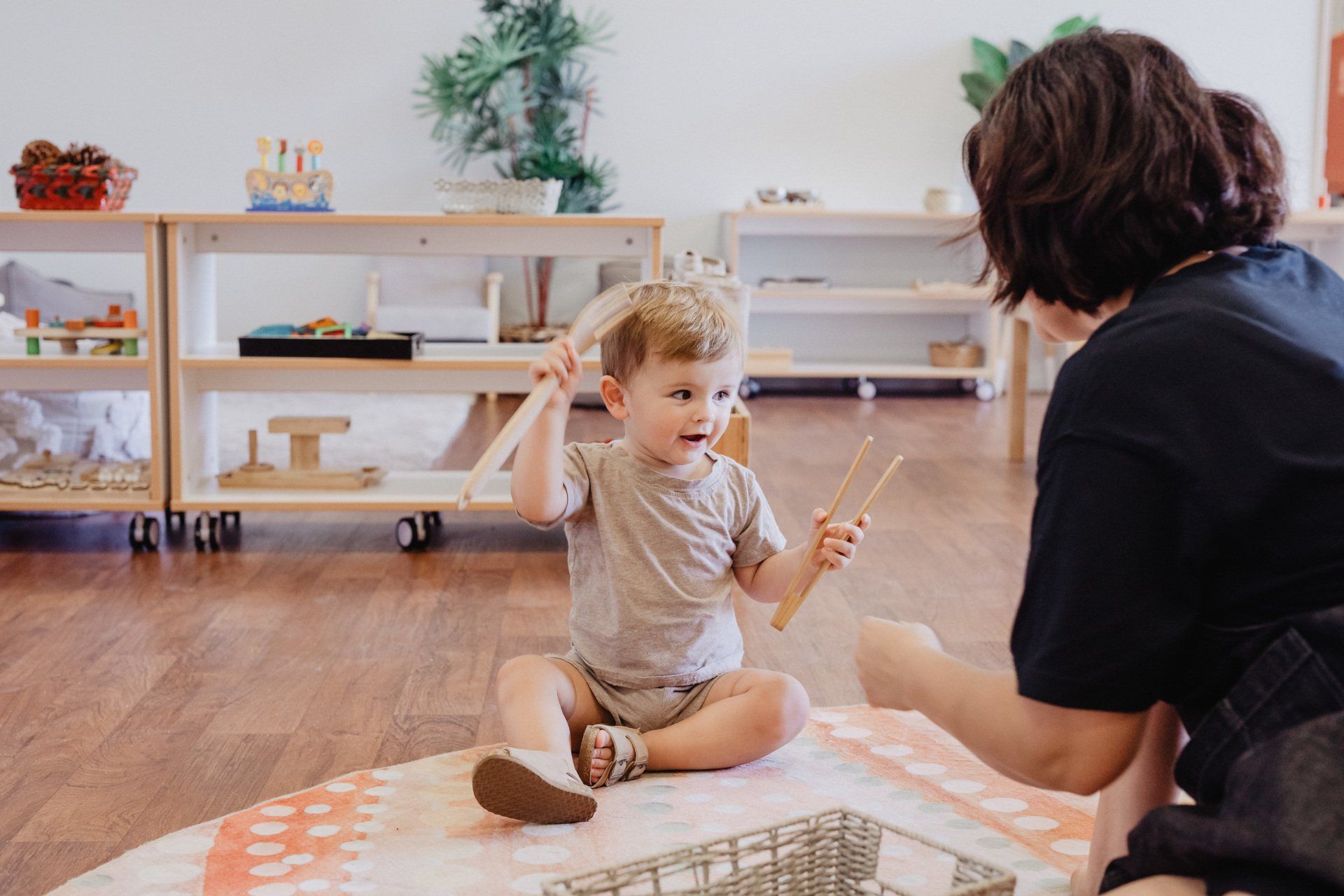 A woman and a child happily engaged with toys in the playroom at Sagewood Joondalup Campus Childcare Centre.