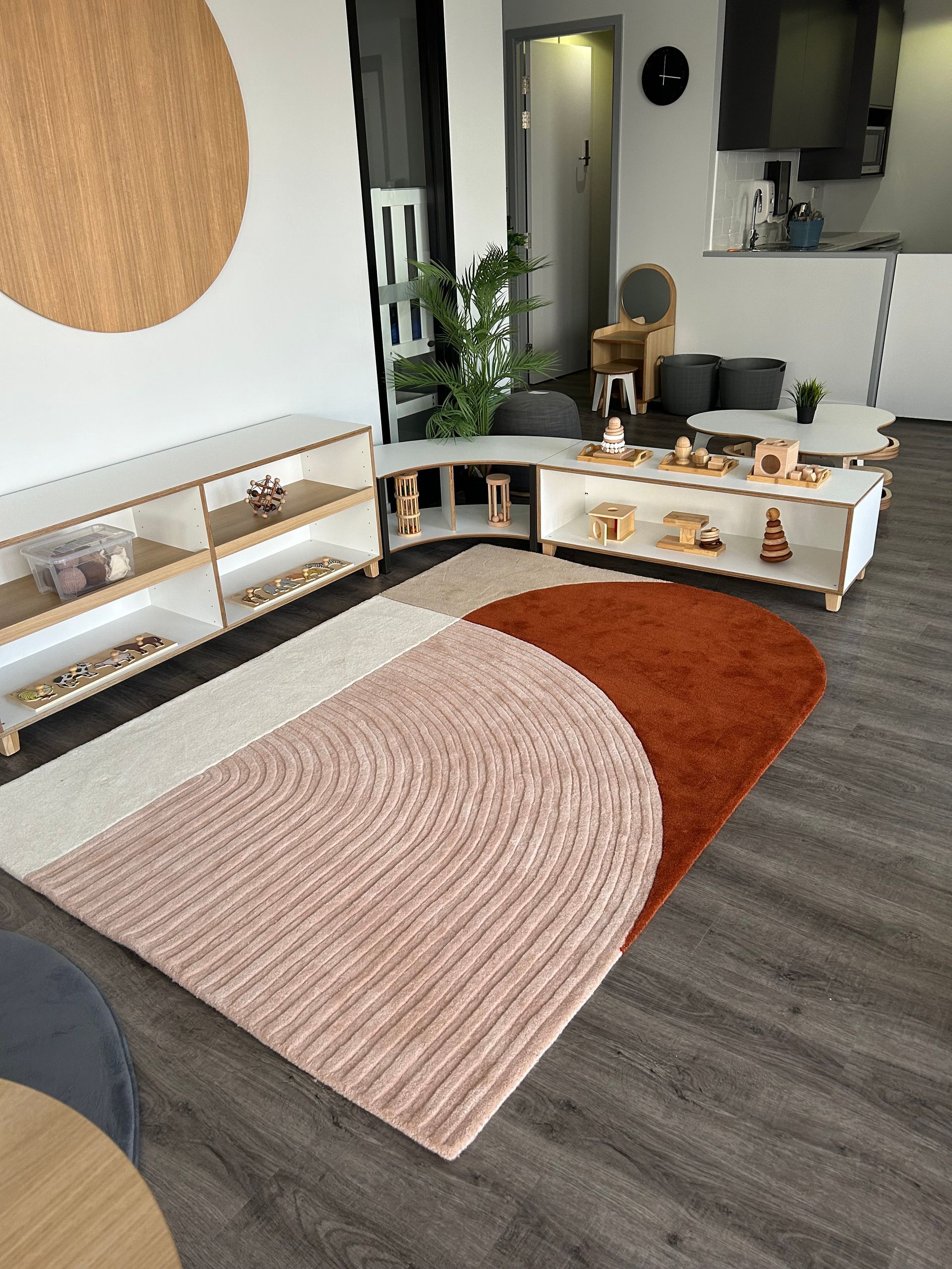 Welcoming living room at Sagewood Woodvale Campus, showcasing a colorful rug and child-friendly furniture for playtime.