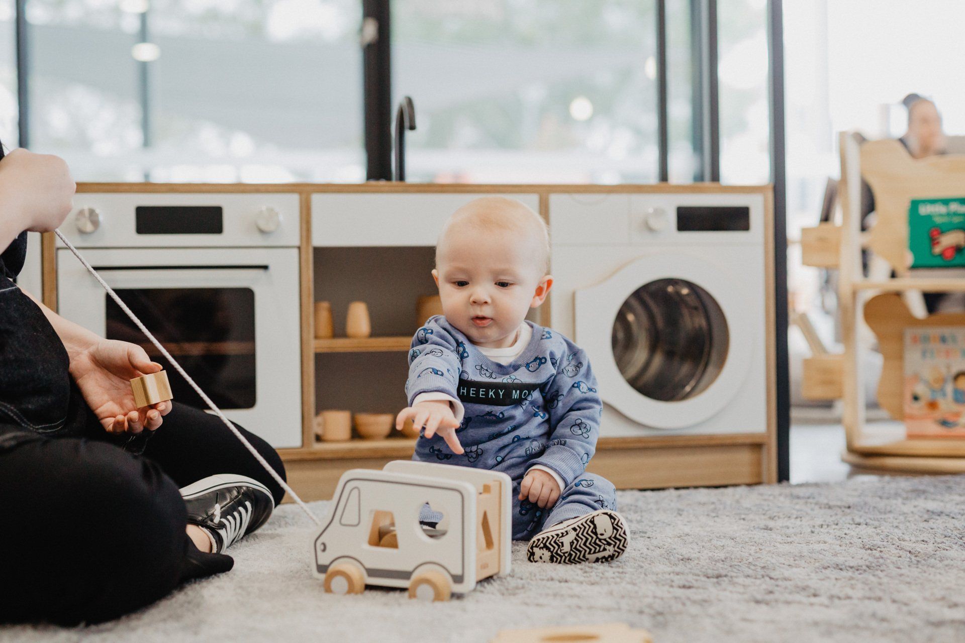 A woman and baby explore wooden toys together in a vibrant playroom at Sagewood Canning Vale Campus - Childcare Centre.