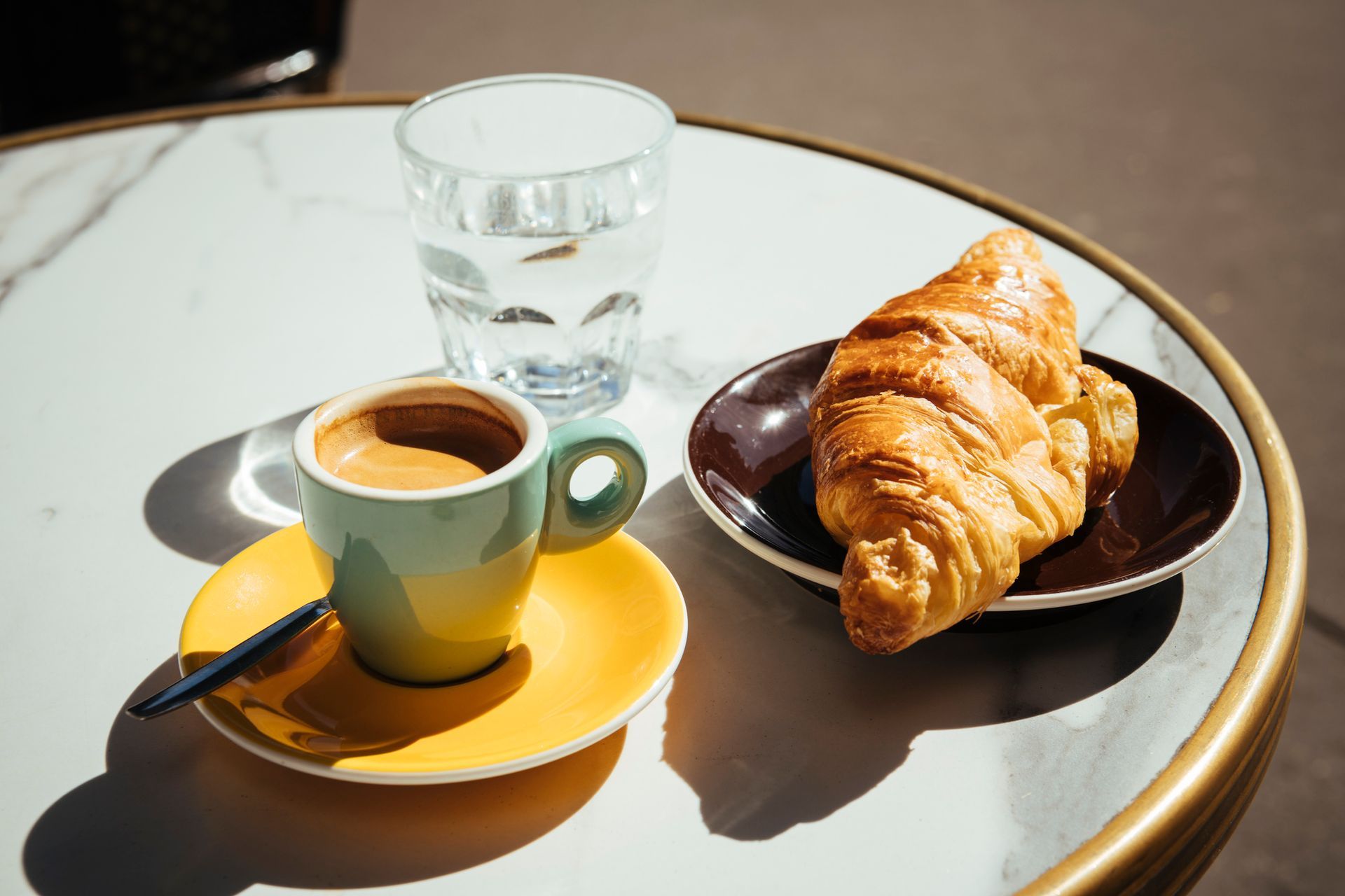 Una tazza di caffè e un croissant sono su un tavolo.