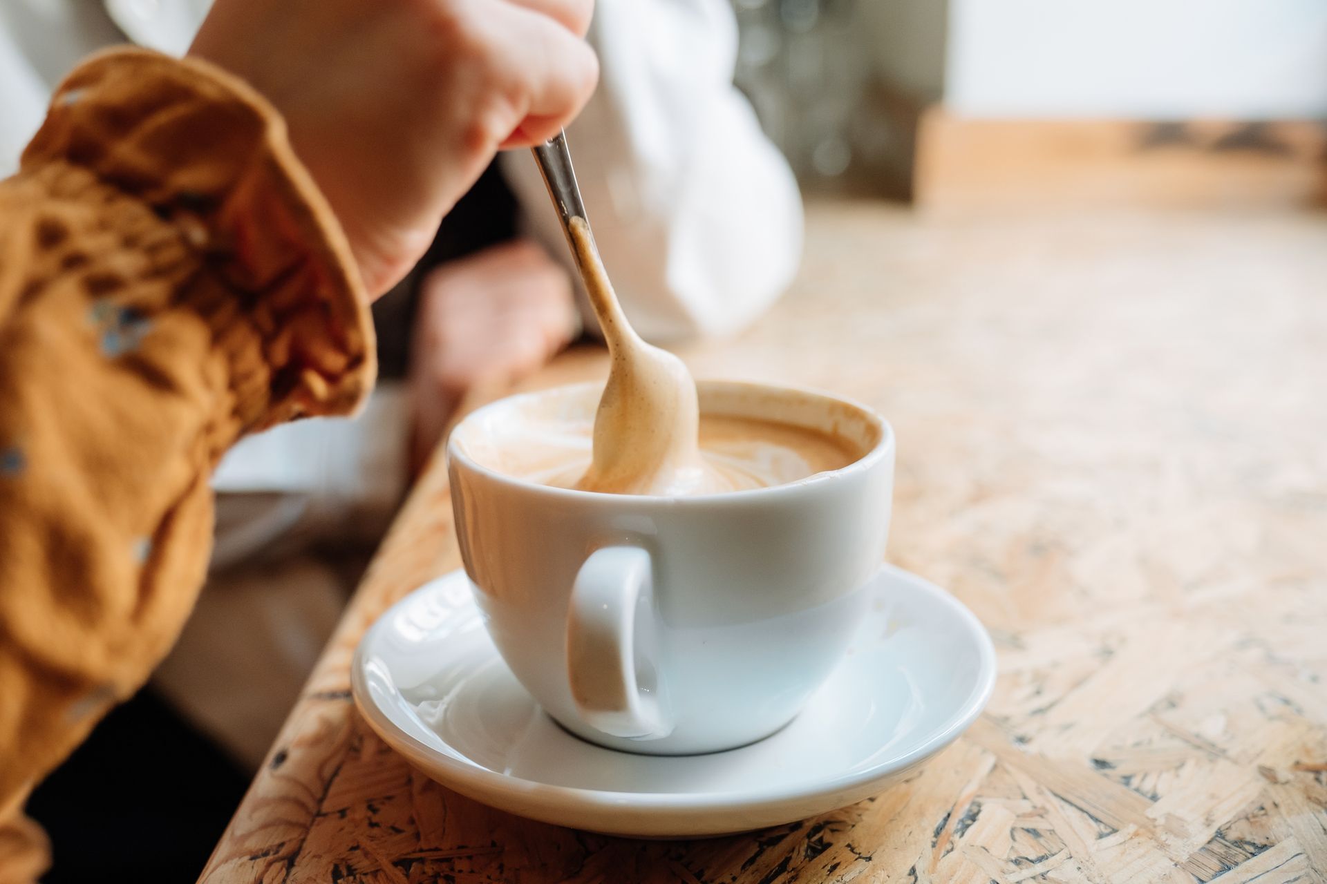 Una persona sta mescolando una tazza di caffè con un cucchiaino.