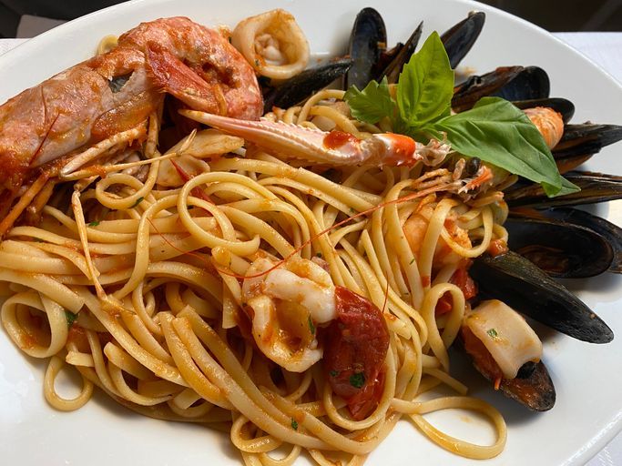 Un piatto bianco condito con spaghetti e frutti di mare