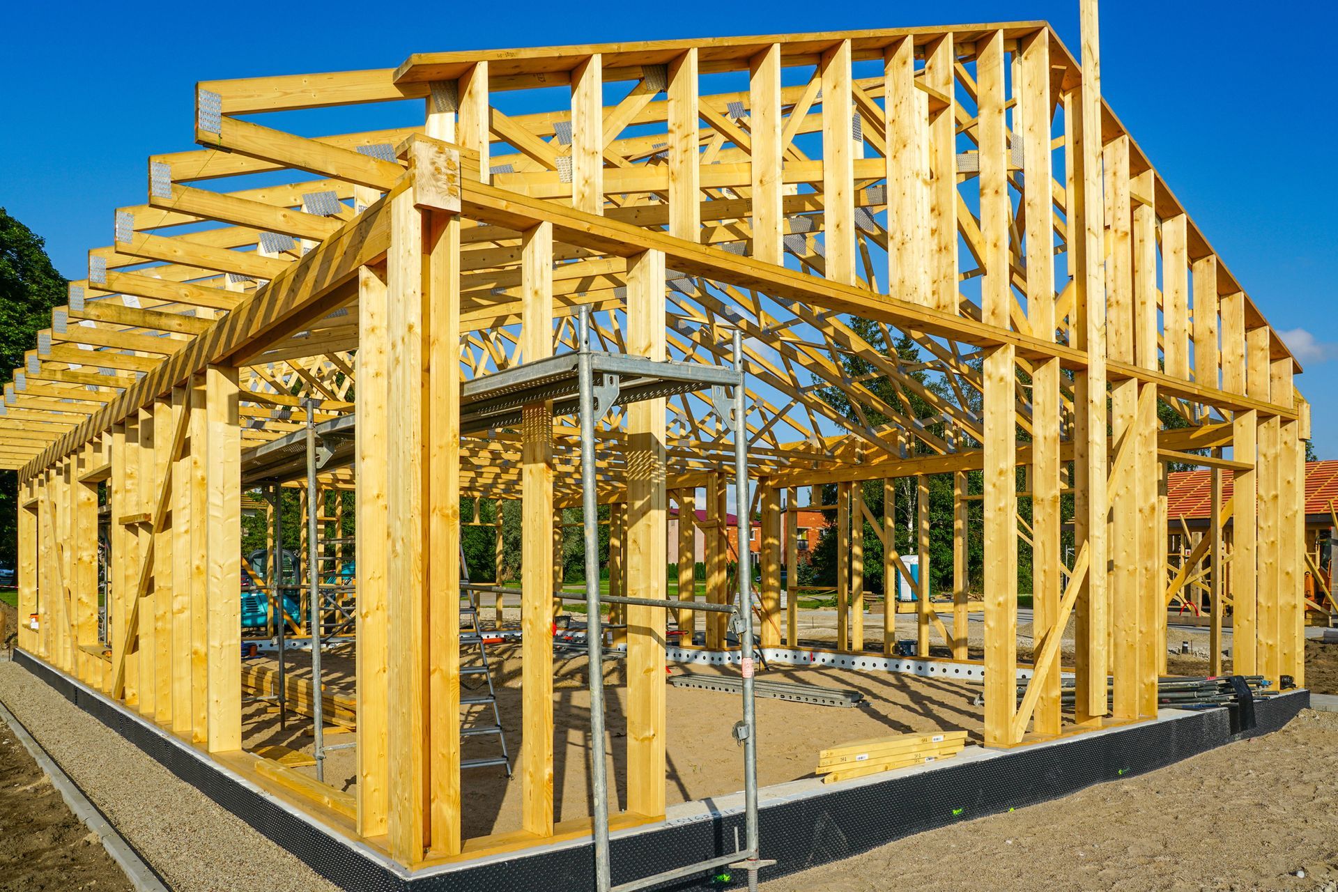 Casa in costruzione con struttura in legno, travi del tetto a vista e cielo azzurro limpido.