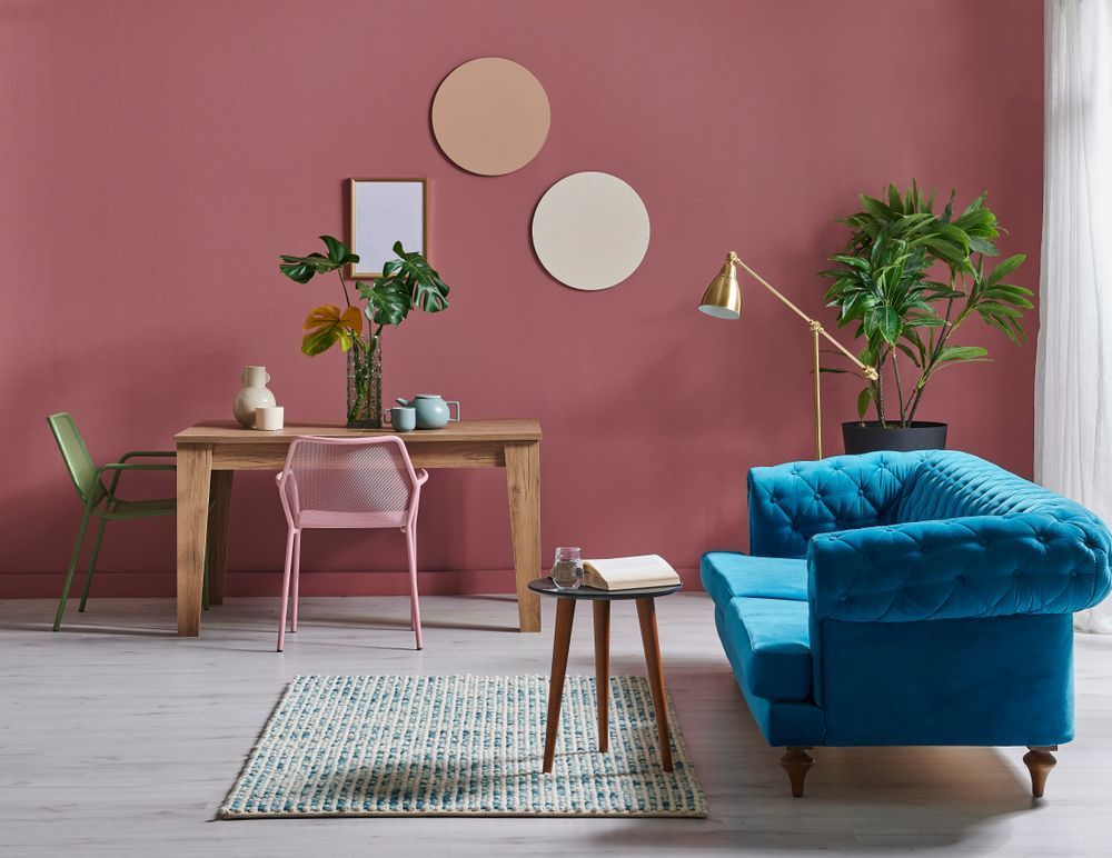 A Living Room With Pink Walls, a Blue Couch, a Table and Chairs — Cairns Floors and More In Trinity Beach, QLD