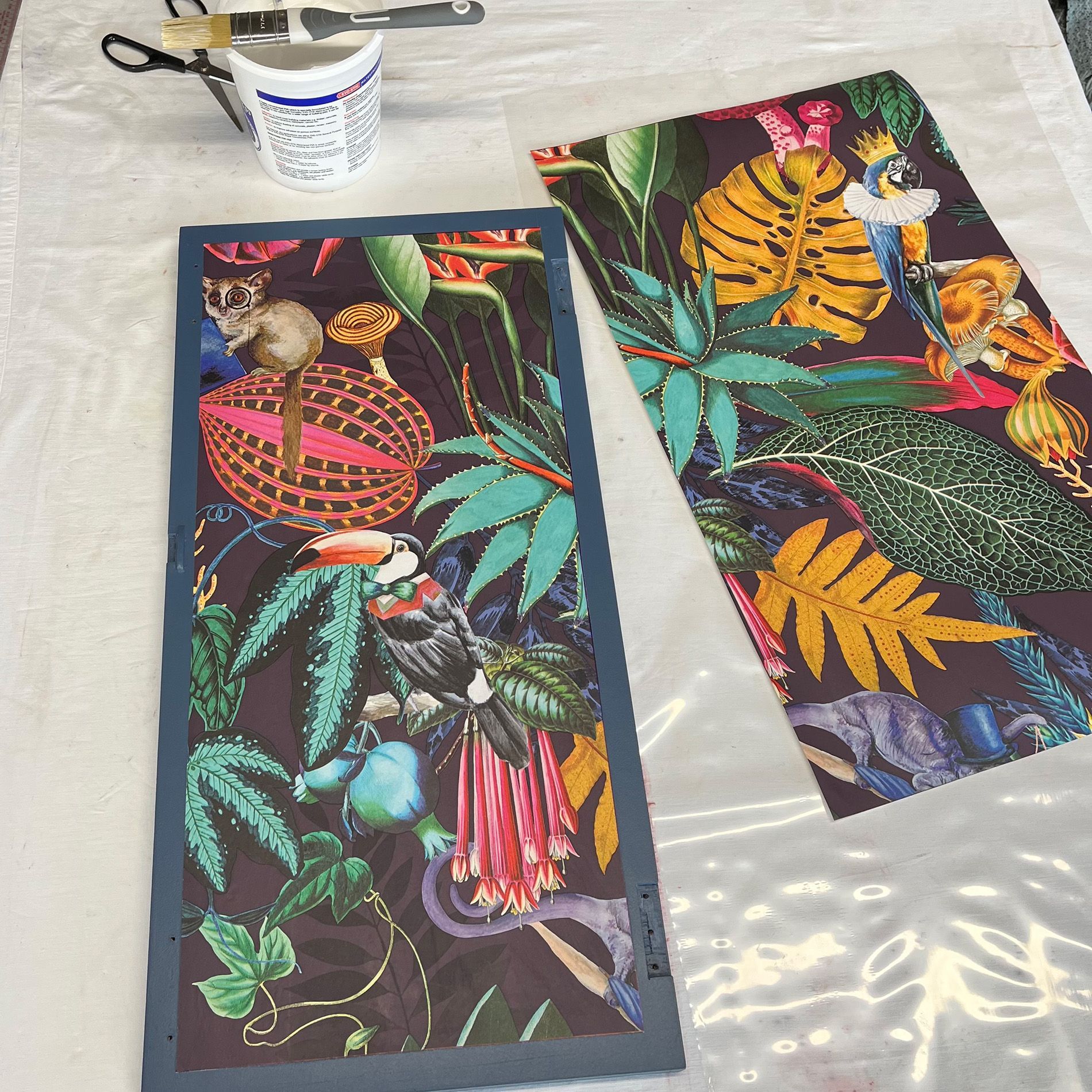 Wall paper panels being stuck on doors of a blue cocktail cabinet.