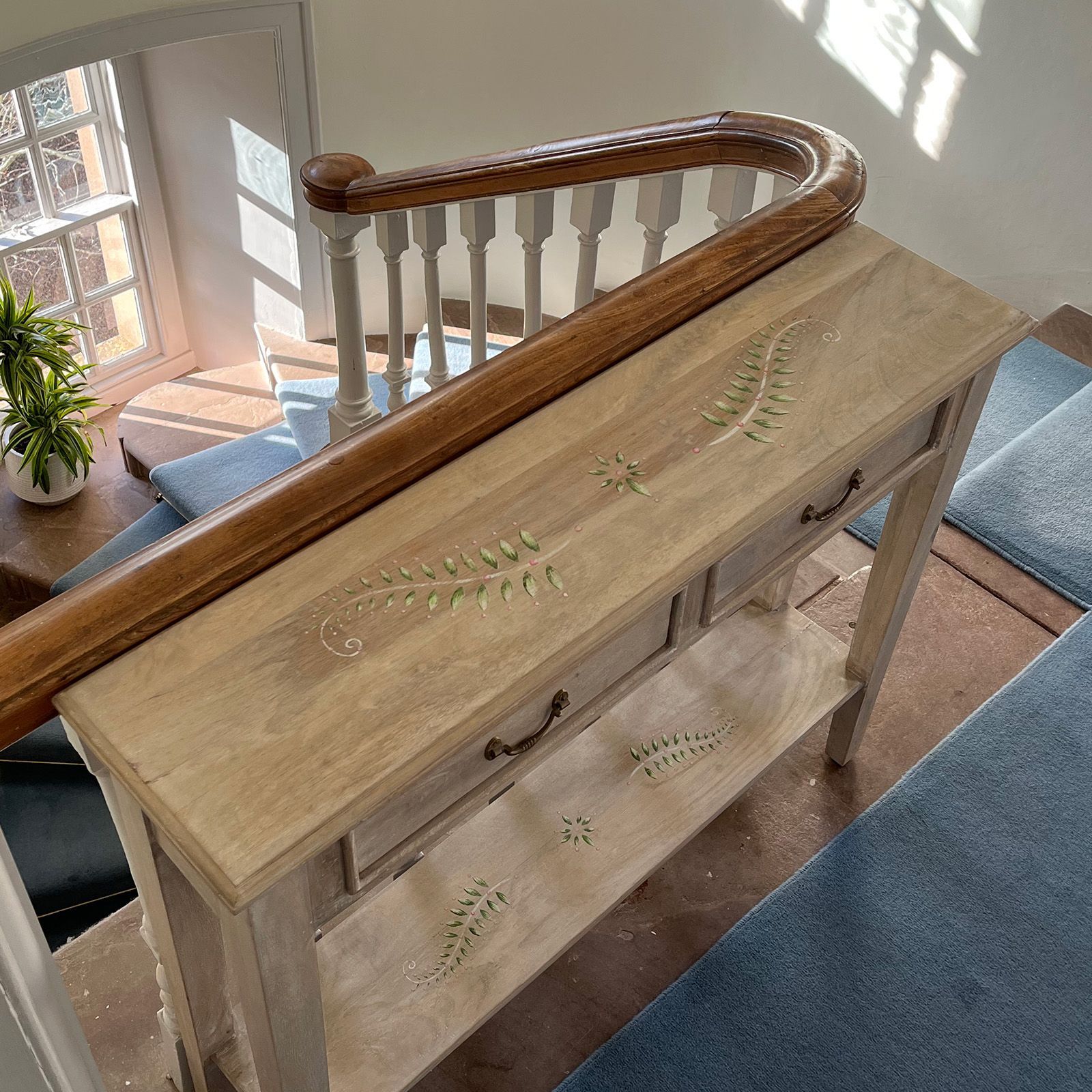 Fern console table at the top of a staircase.