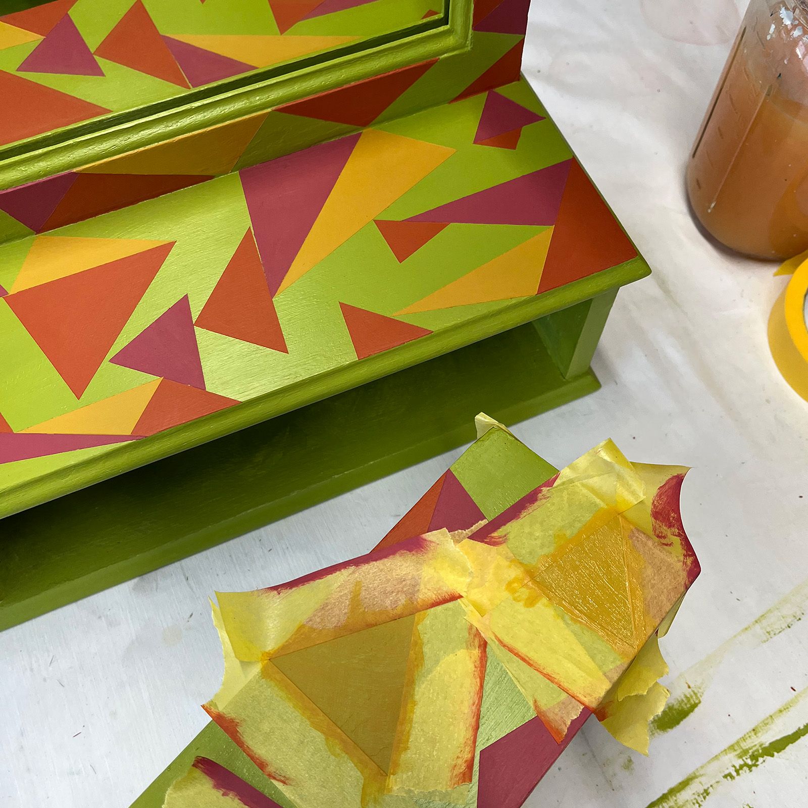 The top coats in  cardinal red, persian rose and french ochre are added using masking tape.