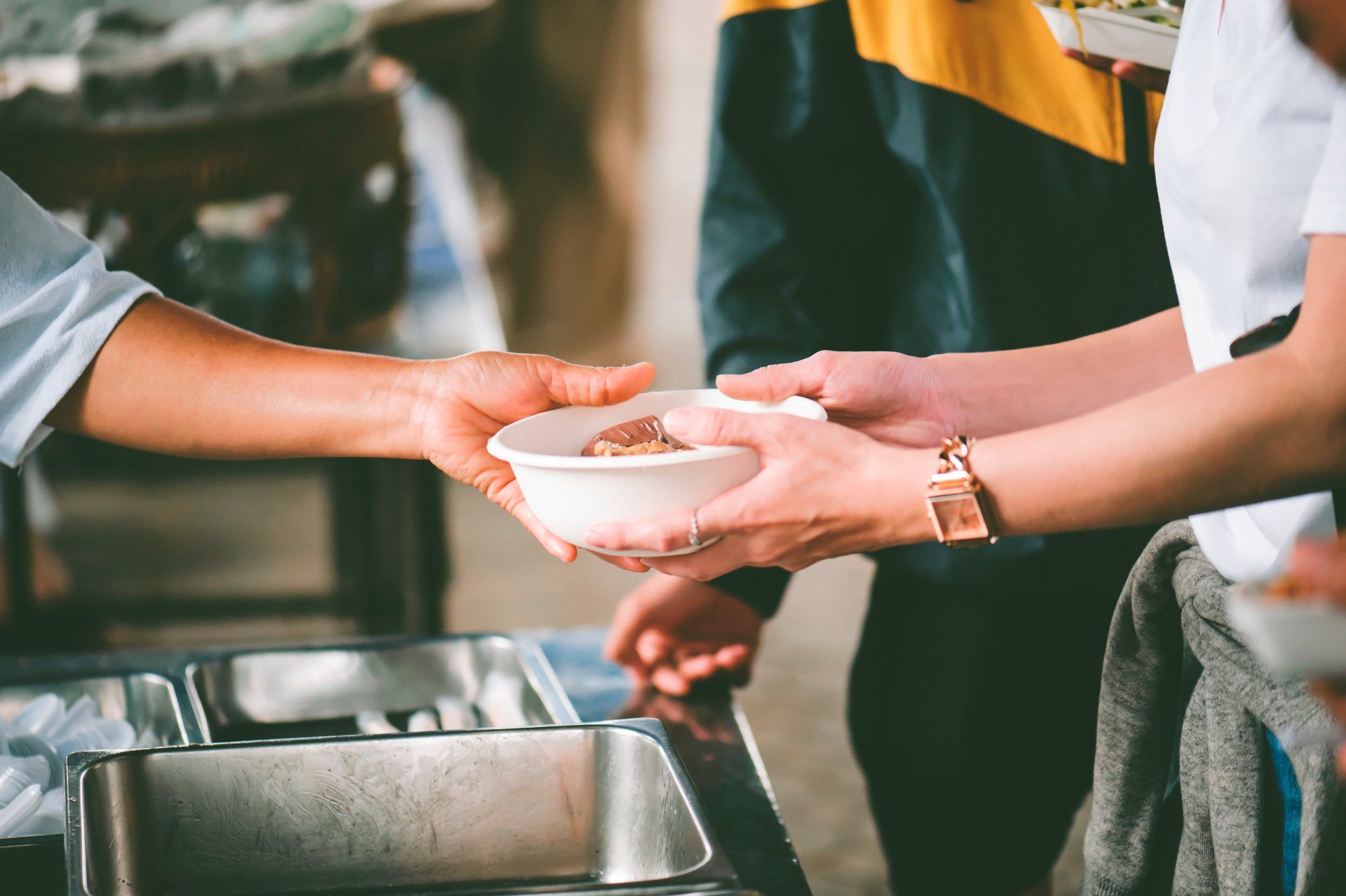 Person giving food to another, food kitchen