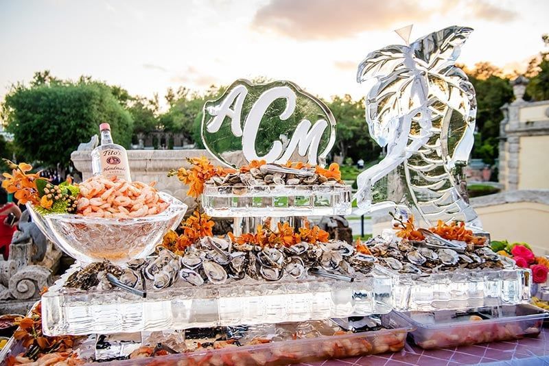 Seafood buffet on ice sculptures, including shrimp cocktail and oysters.
