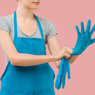 Une femme en tablier bleu met des gants bleus