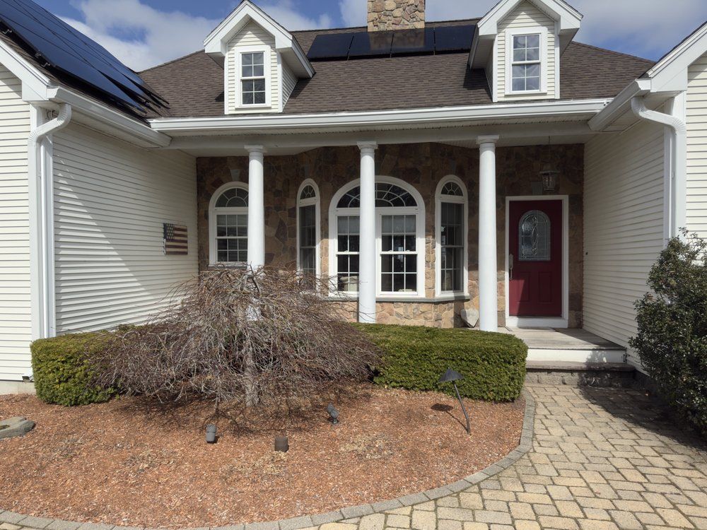 Suburban house front porch with white siding, red door, and brick walkway