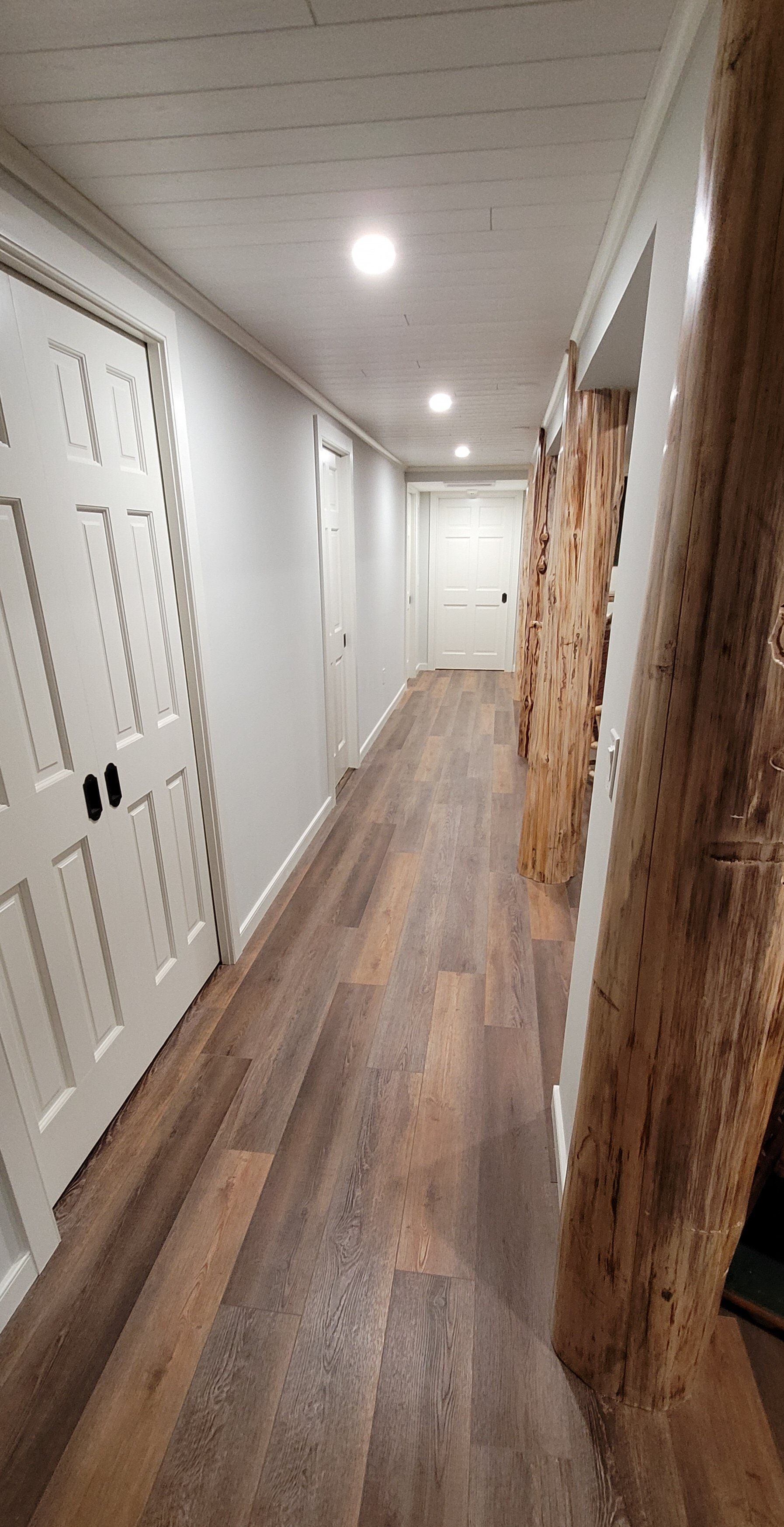 A long hallway with wooden floors and white doors in a house.
