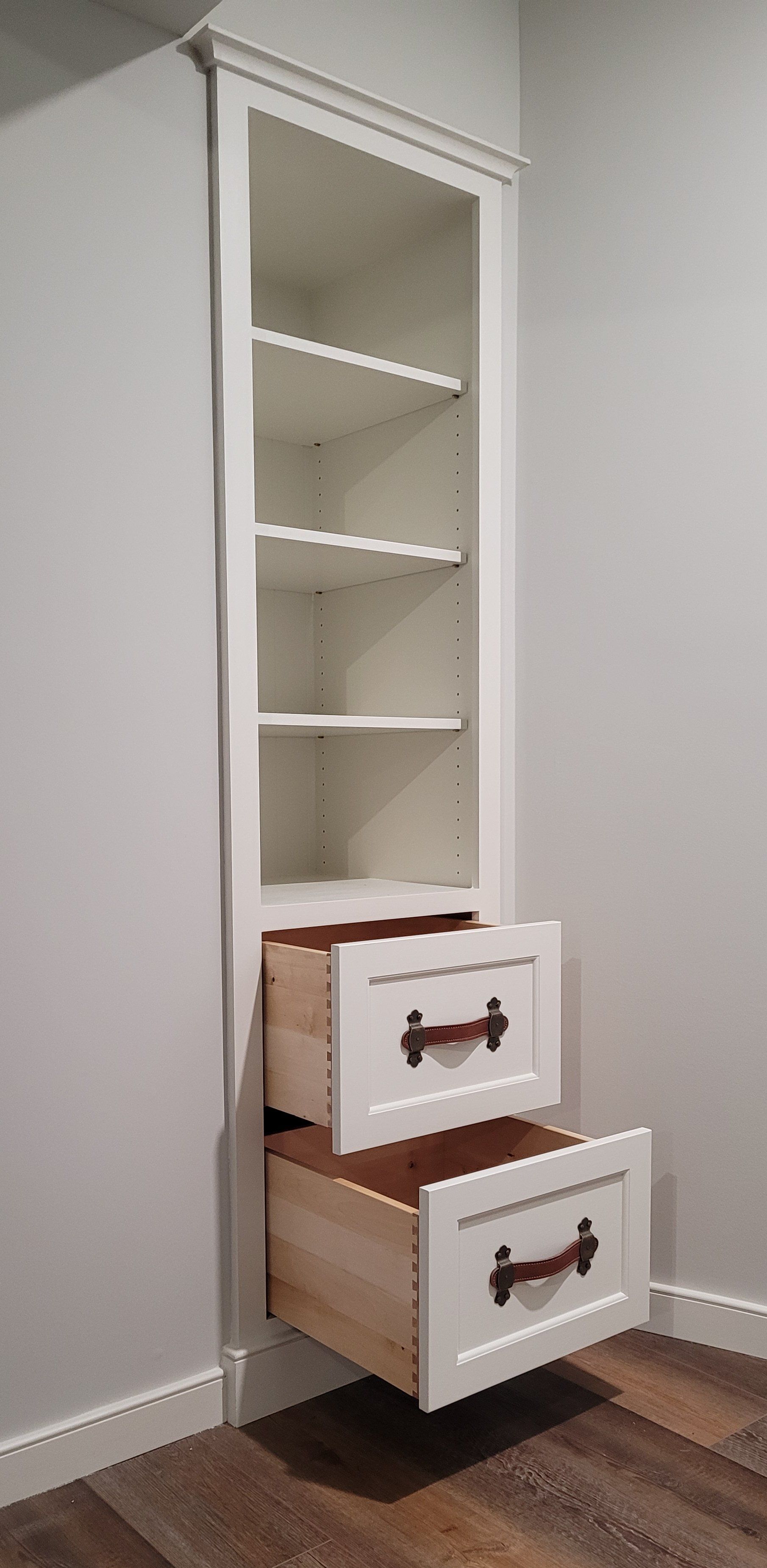 A white cabinet with two drawers and shelves in a room.