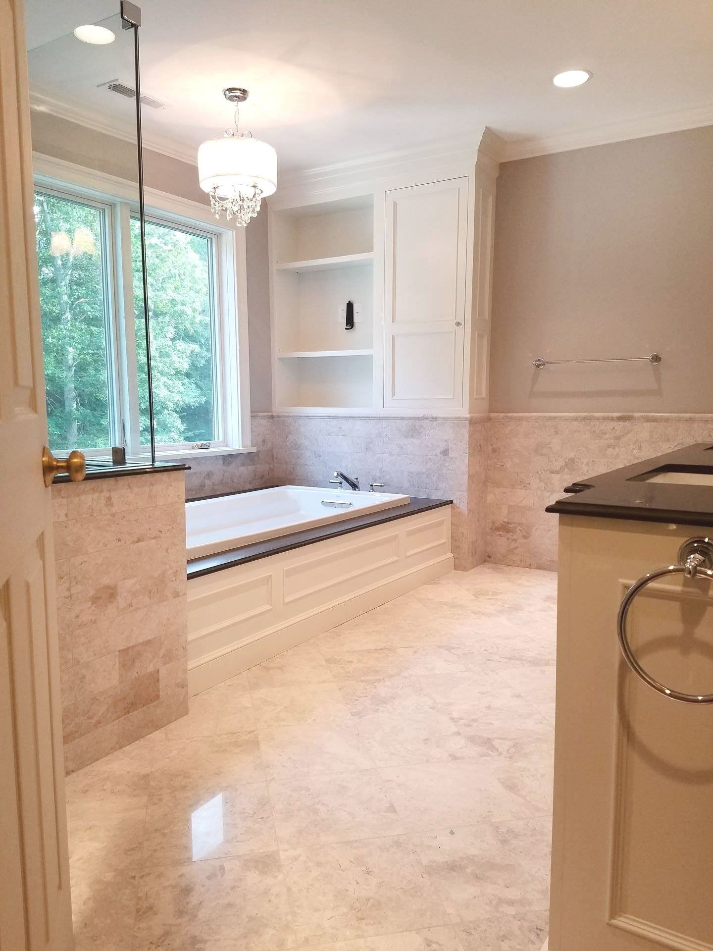 A bathroom with a tub , sink , and window.