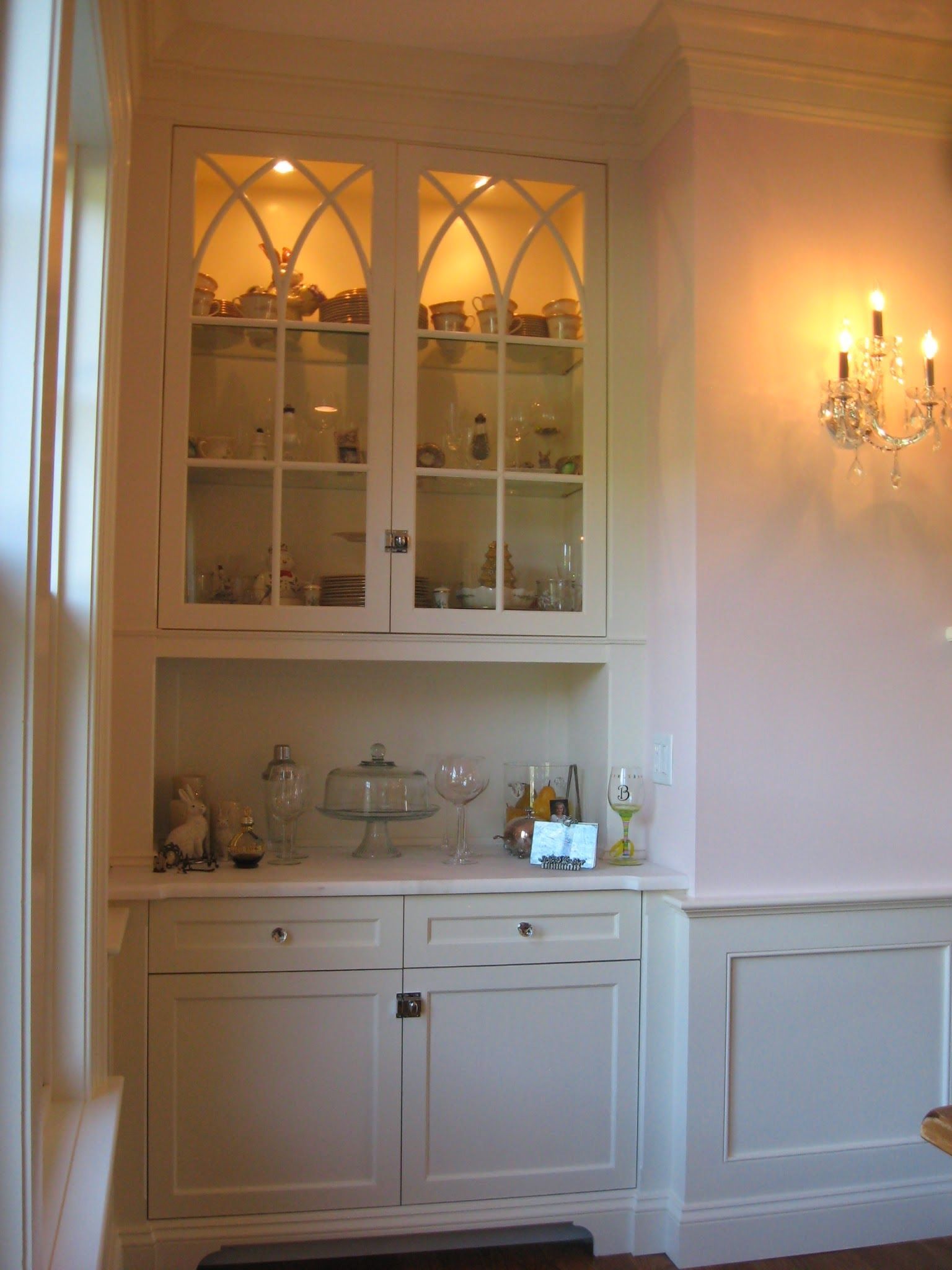 A dining room with white cabinets and glass doors