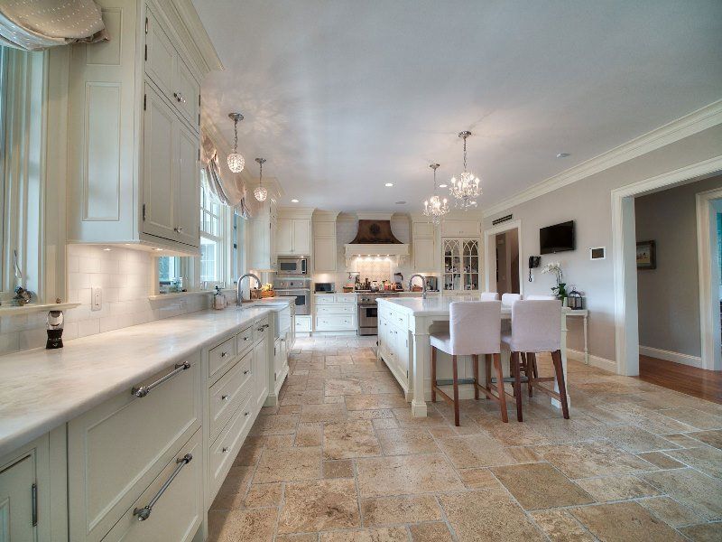 A large kitchen with white cabinets and marble counter tops