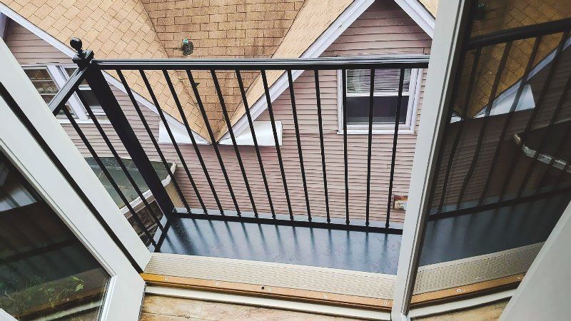A balcony with a metal railing and a view of a house.
