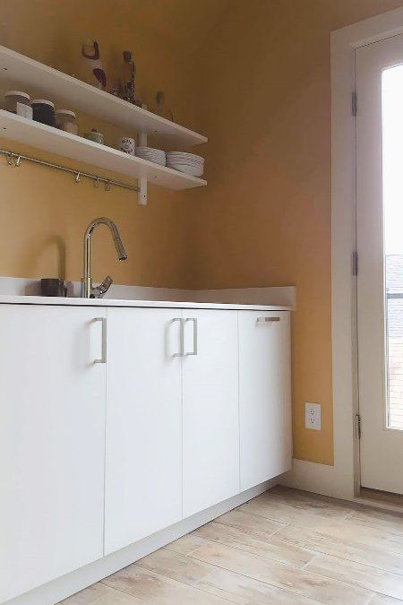 A kitchen with yellow walls and white cabinets and a sink.
