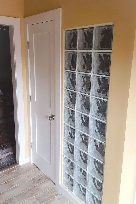 A hallway with a door and a glass block wall.