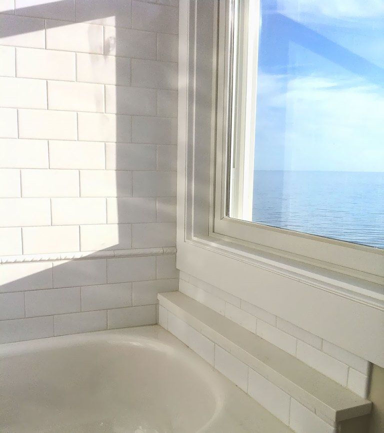 A bathroom with a tub and a window overlooking the ocean