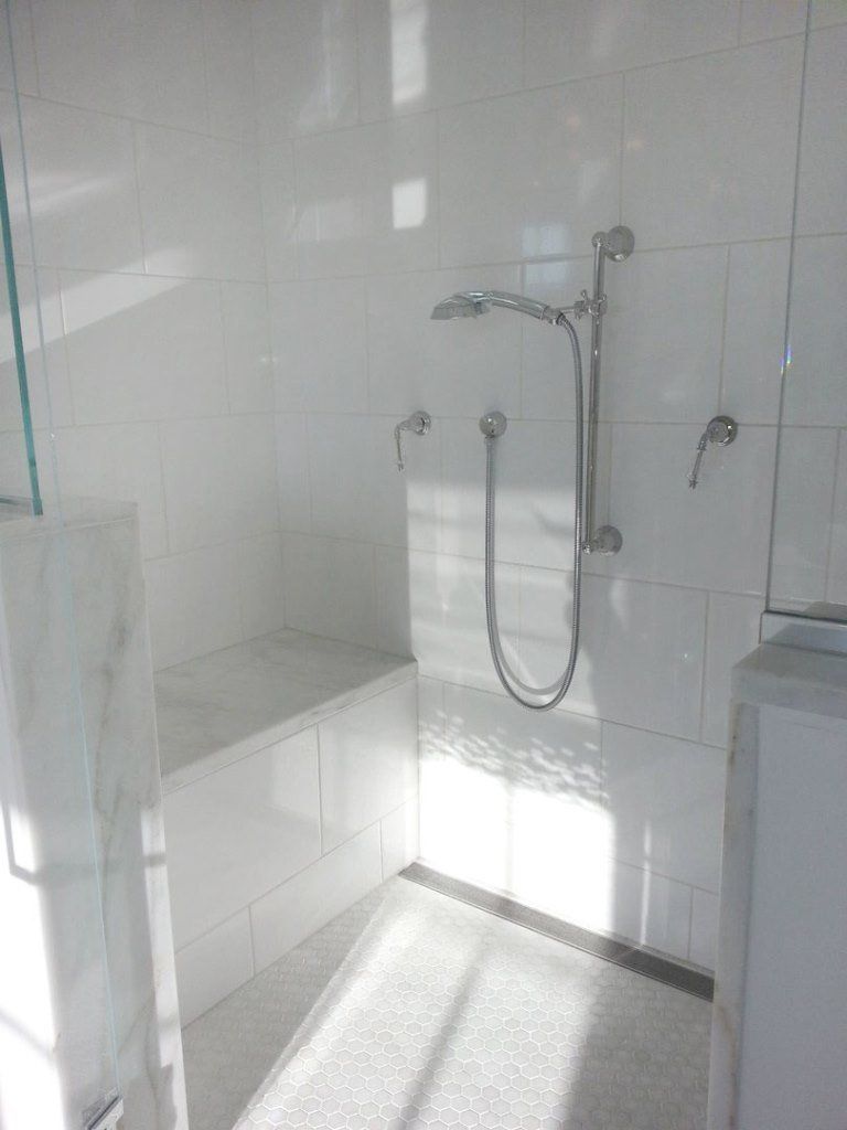 A bathroom with white tiles and a walk in shower.