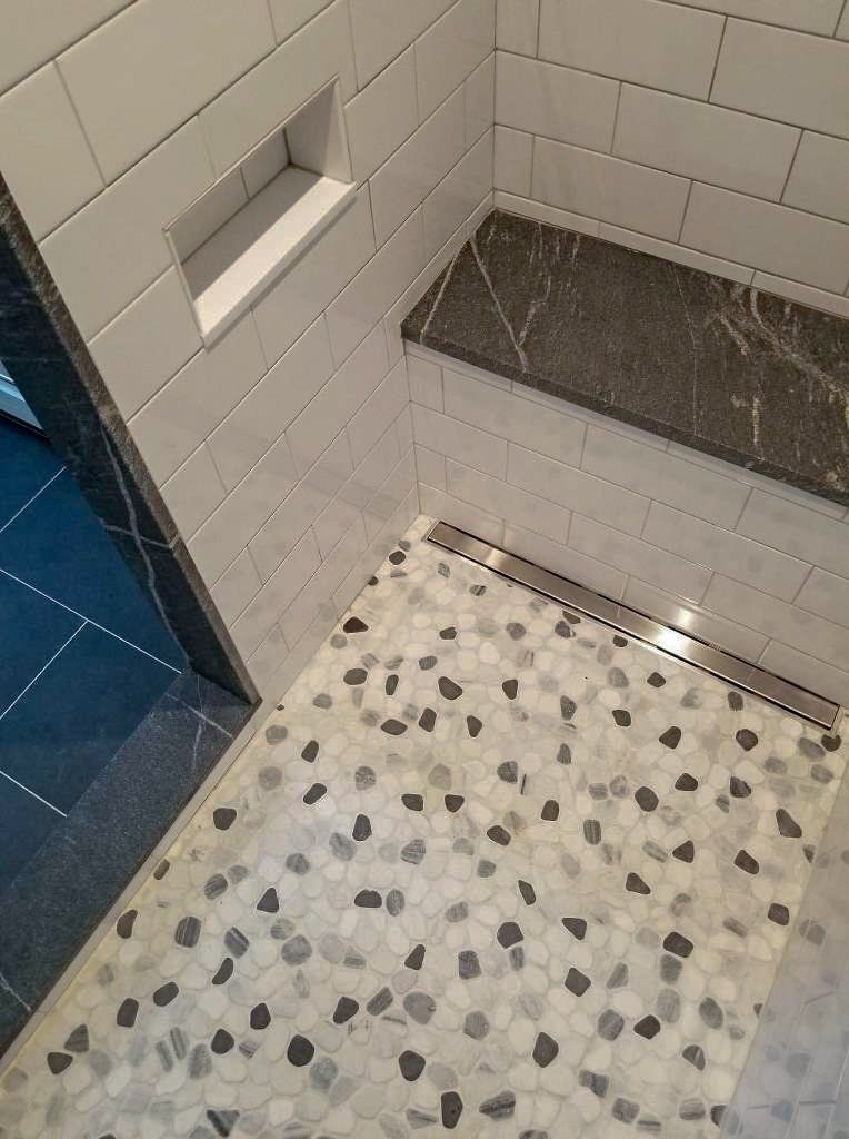 A shower with a bench and a tiled floor.