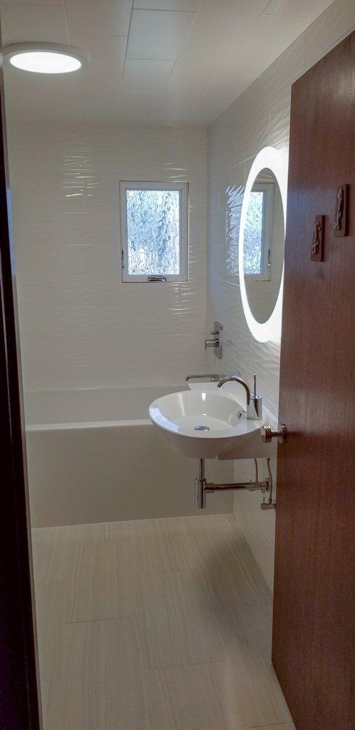 A bathroom with a sink , tub , mirror and window.