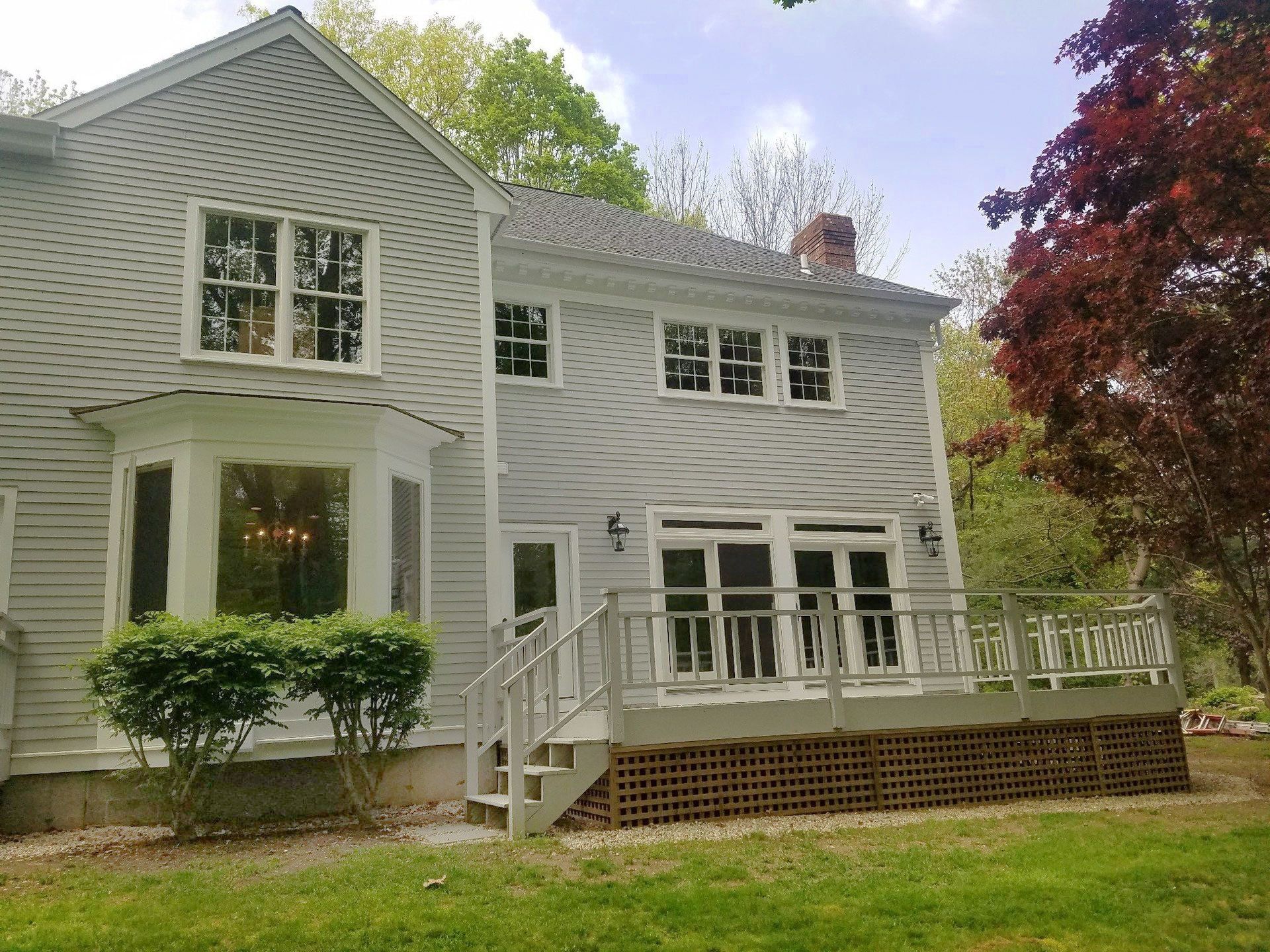 A large white house with a large deck and stairs