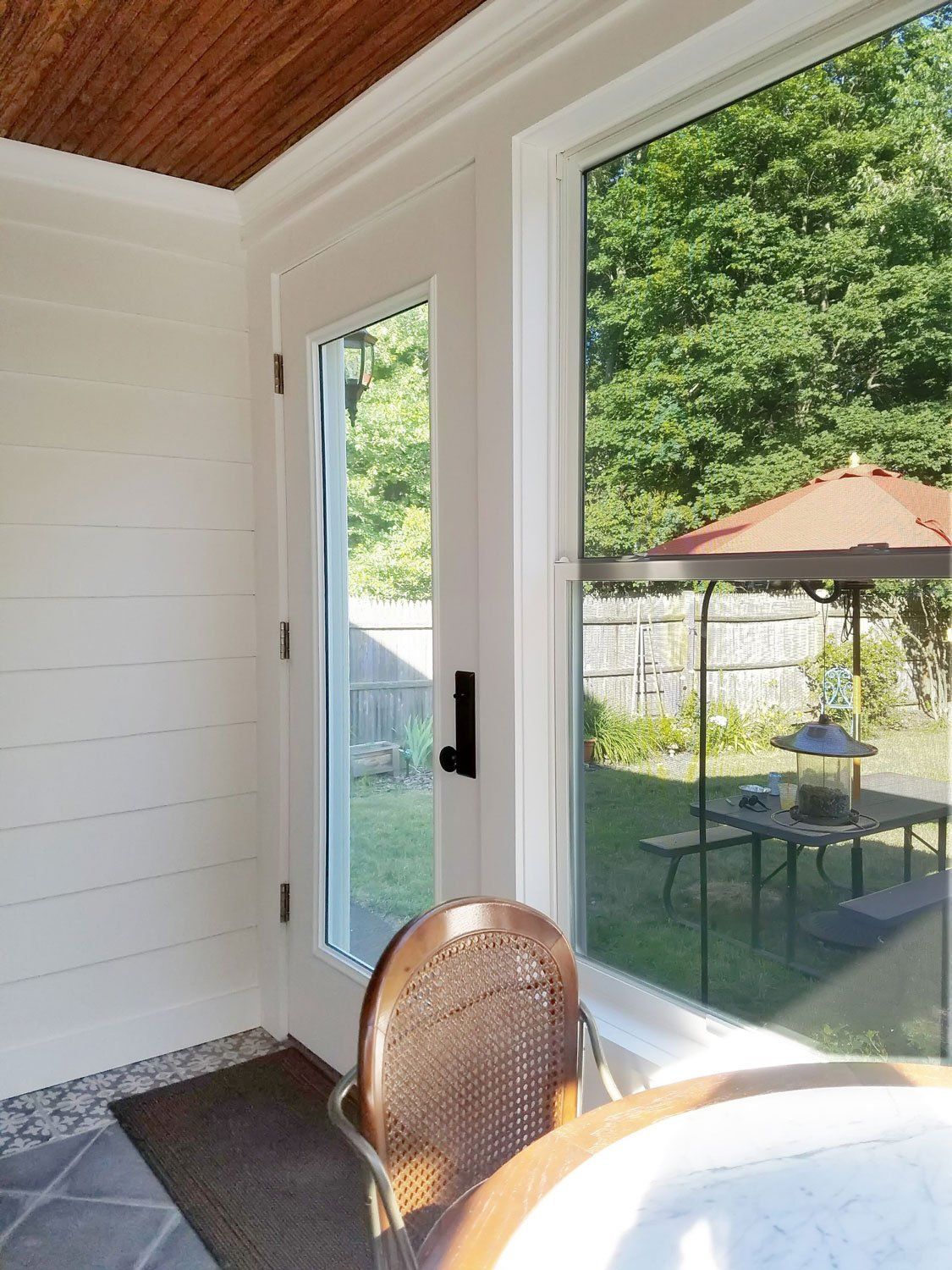 A screened in porch with a table and chairs and a view of the backyard.