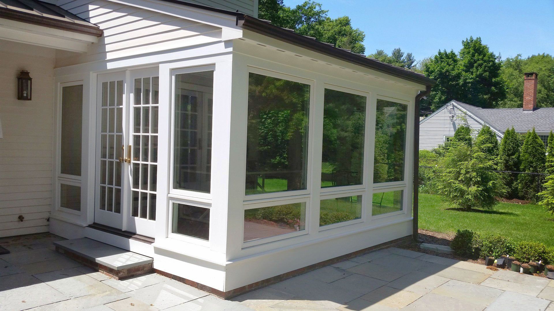 A white house with a screened in porch and a patio.