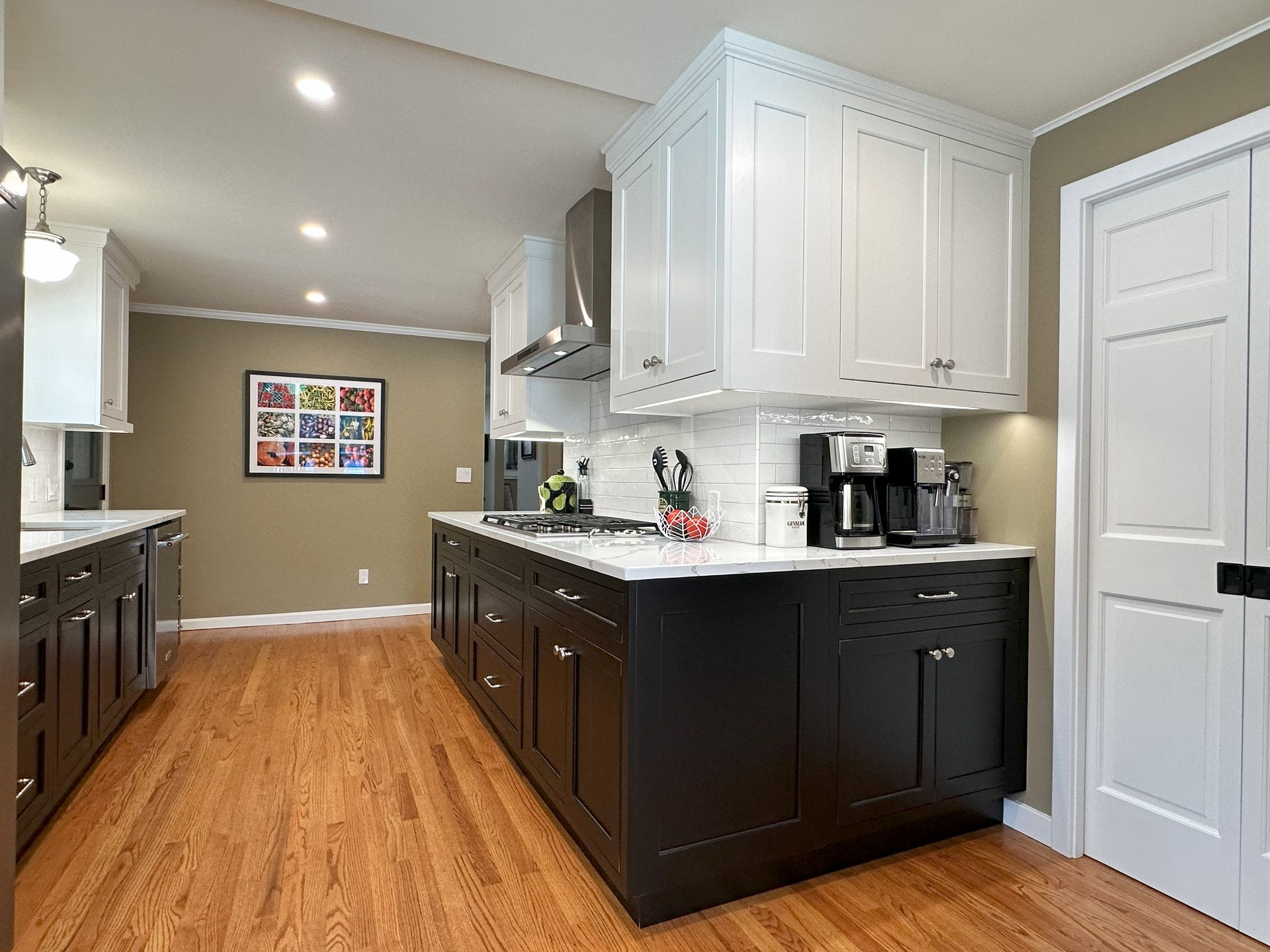 A kitchen with black and white cabinets and hardwood floors.