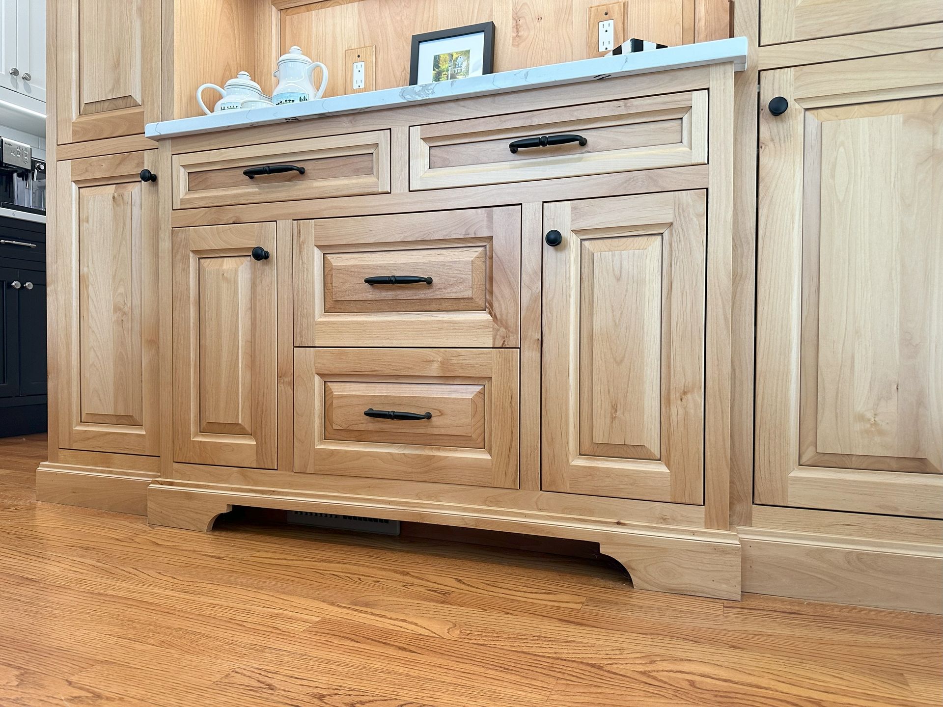 A kitchen with wooden cabinets and drawers and a marble counter top.
